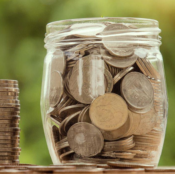 Glass money box jar filled with coins